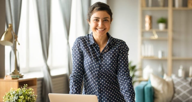 Woman standing near laptop in cozy room