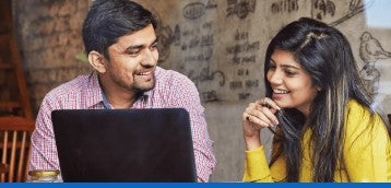 Two young professionals discuss business in front of a laptop
