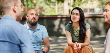 Um grupo de quatro pessoas sentadas ao ar livre e conversando