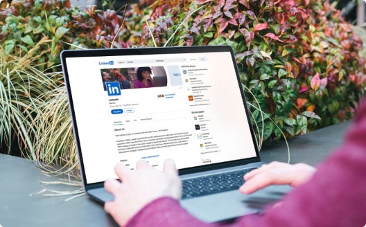 An individual browsing LinkedIn on their laptop outside.